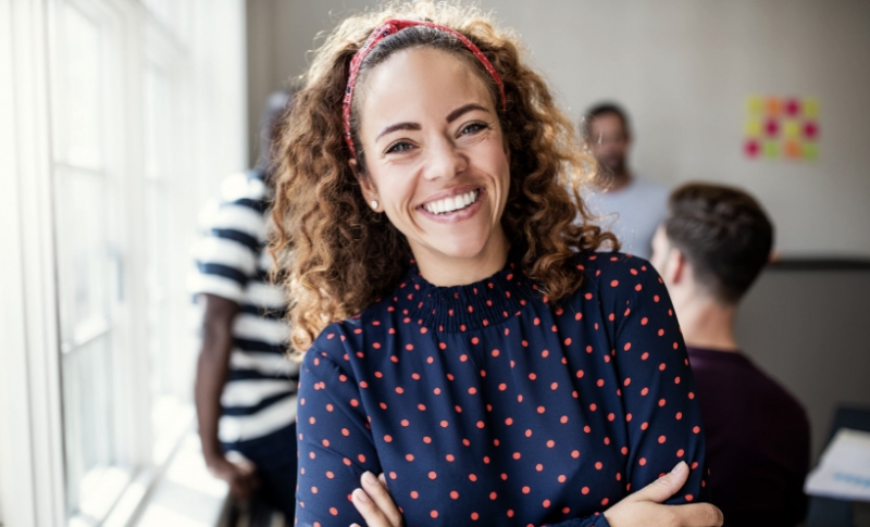 women in blue top with arms crossed, smiling while looking at the camera